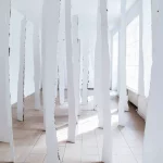 Brzozy zawieszone w przestrzeni i pomalowane z jednej strony bielą tytanową